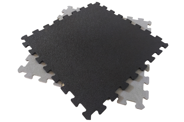 Piso modular em PVC cinzento e preto instalado em oficina, com acabamento antiderrapante e encaixe por módulos.